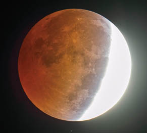 A star shines below the partially eclipsed moon Wednesday morning October 8, 2014 in this picture made through an amateur astronomer's 8-inch telescope at 6:06 a.m.
